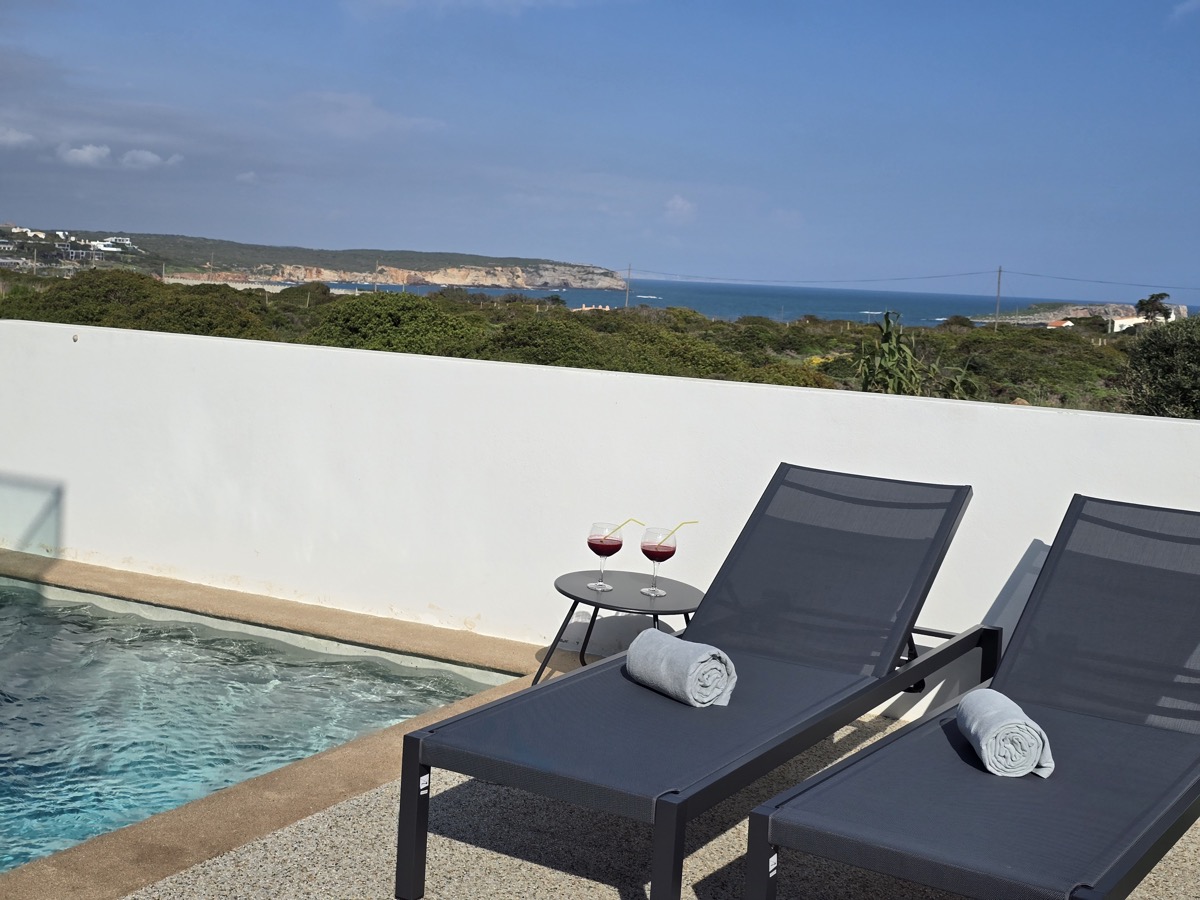 Pool sunbeds with wine glasses and sea view