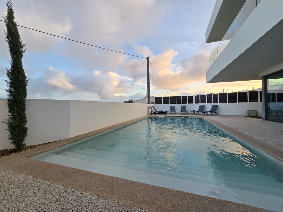 Villa pool at sunset with lounge chairs